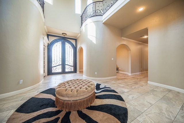 entrance foyer featuring ornamental molding, a towering ceiling, and french doors