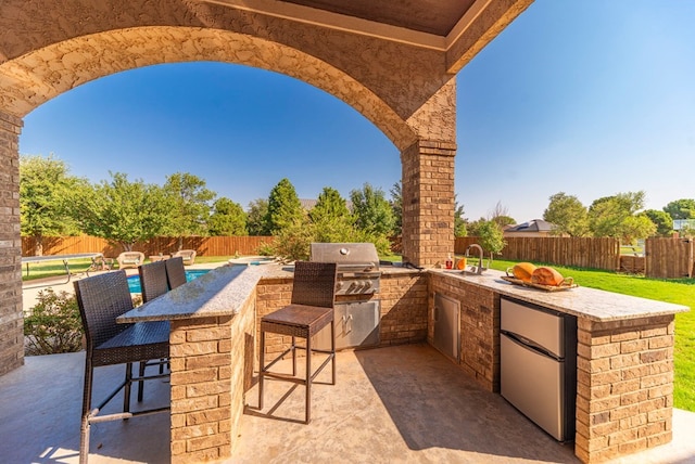 view of patio / terrace featuring a grill, exterior kitchen, and a wet bar