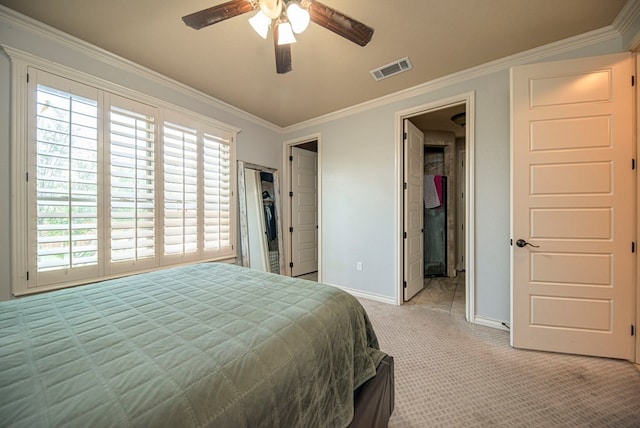 bedroom featuring connected bathroom, ceiling fan, light colored carpet, a walk in closet, and ornamental molding