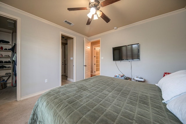 bedroom featuring a walk in closet, ceiling fan, crown molding, and light carpet