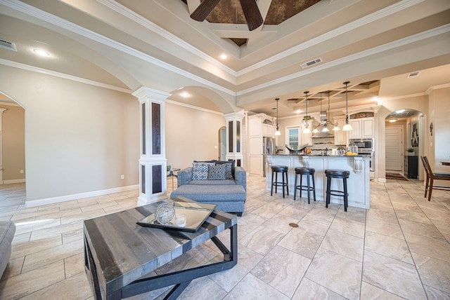 living room with a tray ceiling, ornate columns, and ornamental molding