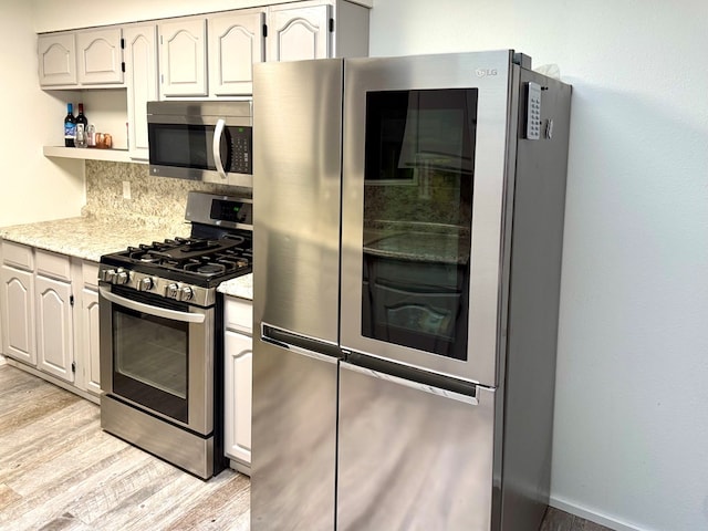 2204 Regal Pl, Midland, TX 79707 - kitchen featuring stainless steel appliances, light wood-style floors, decorative backsplash, open shelves, and light stone countertops