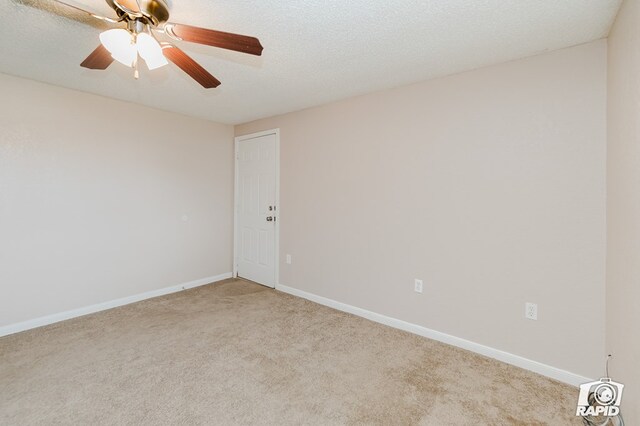 empty room with ceiling fan, a textured ceiling, and light carpet