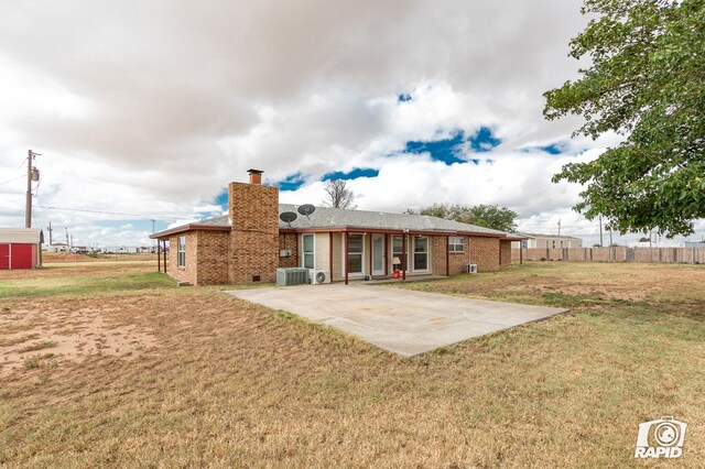 rear view of property with a yard, a patio, and central AC