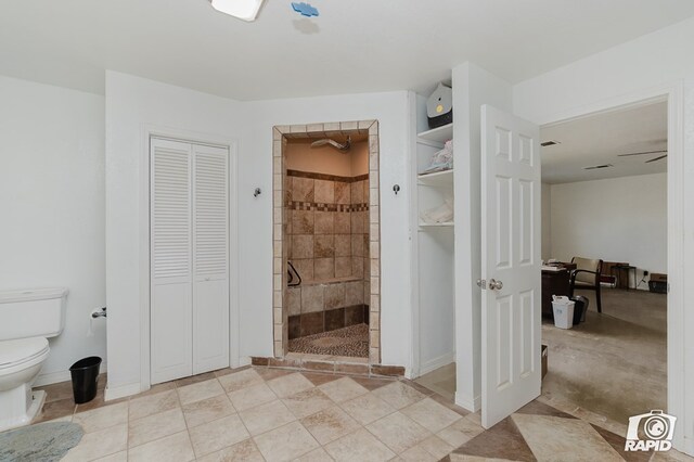 bathroom with a tile shower, ceiling fan, tile patterned flooring, and toilet