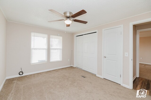 unfurnished bedroom featuring a textured ceiling, ceiling fan, and light carpet