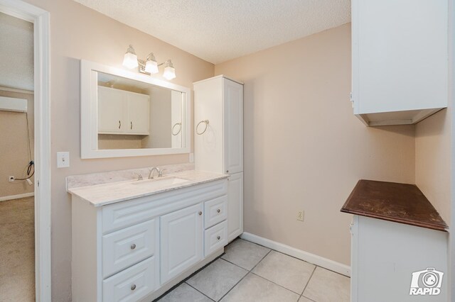 bathroom with tile patterned flooring, vanity, and a textured ceiling