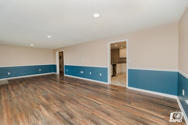 empty room featuring a textured ceiling, sink, and dark hardwood / wood-style floors