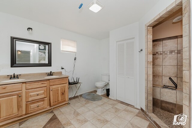 bathroom with vanity, toilet, and tiled shower