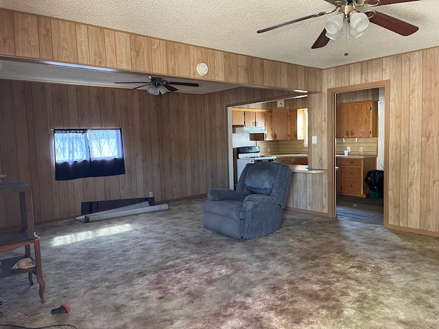 unfurnished living room featuring wooden walls, carpet floors, and a textured ceiling