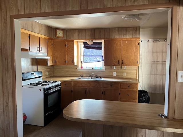 kitchen with kitchen peninsula, white gas range, sink, and tasteful backsplash