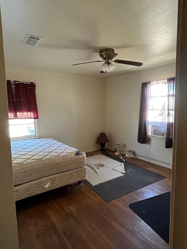 unfurnished bedroom with multiple windows, ceiling fan, and dark hardwood / wood-style flooring