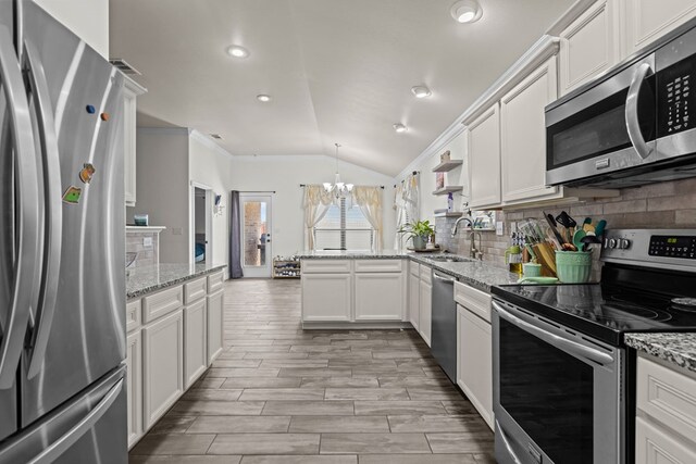 1220 Wrangler Ln, Midland, TX 79705 - kitchen featuring a peninsula, a sink, lofted ceiling, stainless steel appliances, and a notable chandelier