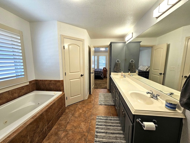 916-B Bronstad Dr, Andrews, TX 79714 - ensuite bathroom featuring double vanity, a whirlpool tub, a textured ceiling, and tile patterned flooring