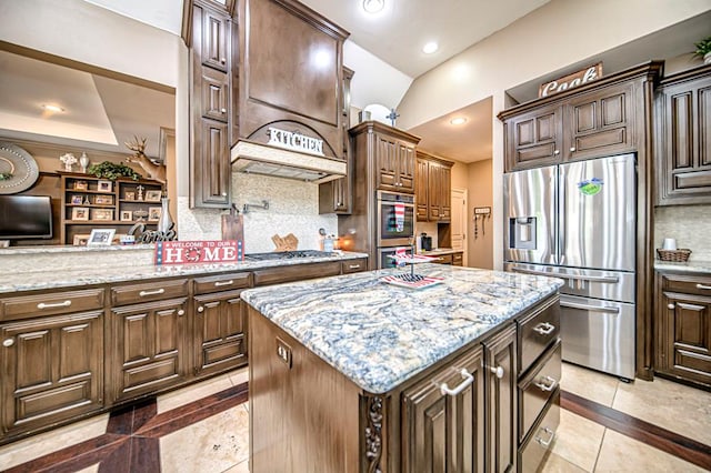 kitchen with a center island, decorative backsplash, light tile patterned floors, appliances with stainless steel finishes, and light stone counters