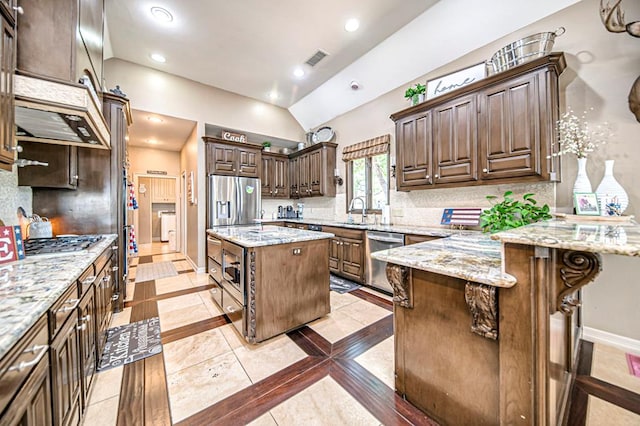 kitchen featuring a kitchen island, light stone counters, stainless steel appliances, and a breakfast bar area