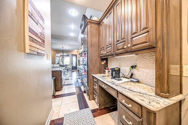 kitchen featuring light stone countertops, a notable chandelier, pendant lighting, decorative backsplash, and light tile patterned floors