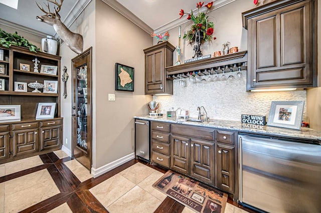 kitchen with sink, crown molding, stainless steel fridge, dark tile patterned floors, and dark brown cabinets