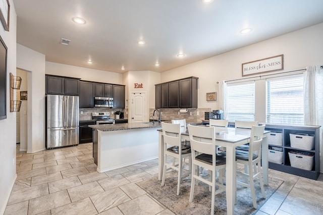 kitchen with a sink, stainless steel appliances, tasteful backsplash, visible vents, and dark brown cabinets