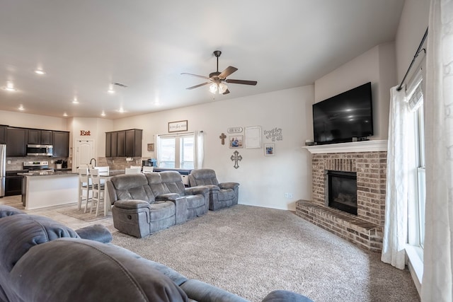 living area with visible vents, light carpet, ceiling fan, and a brick fireplace