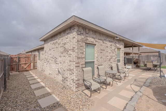 rear view of house featuring a gate, a patio area, brick siding, and a fenced backyard
