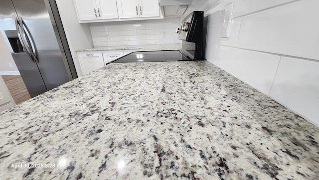 1104 Osprey Dr, Midland, TX 79706 - details with stainless steel refrigerator with ice dispenser, white cabinetry, backsplash, light stone countertops, and range with electric cooktop