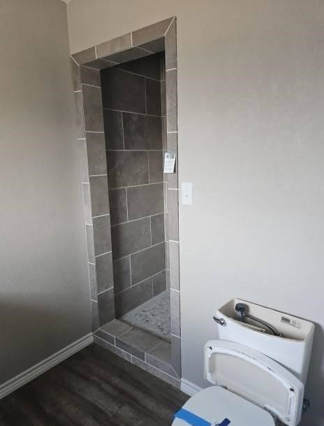 1204 Boykin Rd, Big Spring, TX 79720 - full bath with tiled shower, toilet, wood finished floors, and baseboards