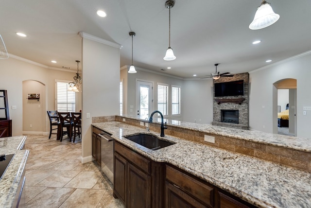 kitchen featuring light stone counters, hanging light fixtures, crown molding, and sink