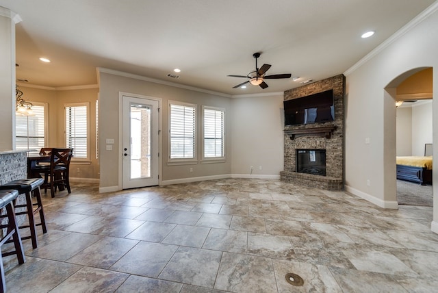 living room with plenty of natural light, a large fireplace, crown molding, and ceiling fan with notable chandelier