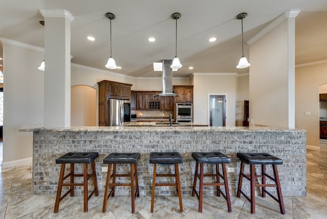 kitchen featuring island range hood, ornamental molding, a breakfast bar area, and appliances with stainless steel finishes