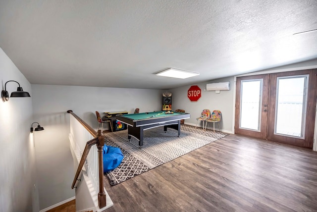 recreation room with a textured ceiling, wood finished floors, a wall unit AC, pool table, and baseboards