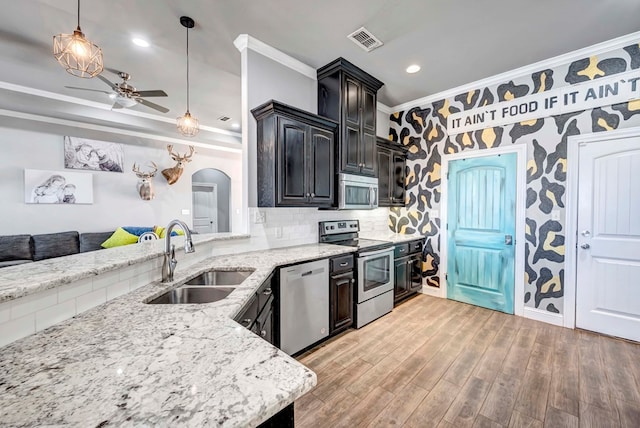 kitchen featuring visible vents, a sink, arched walkways, appliances with stainless steel finishes, and light wood finished floors