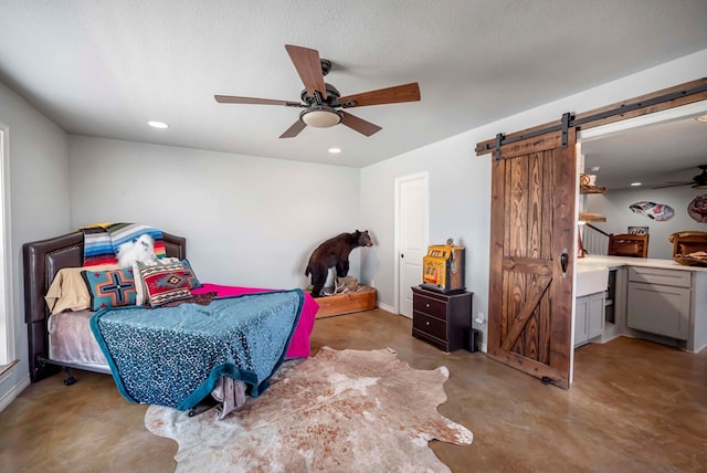 bedroom featuring a ceiling fan, recessed lighting, finished concrete floors, a textured ceiling, and a barn door