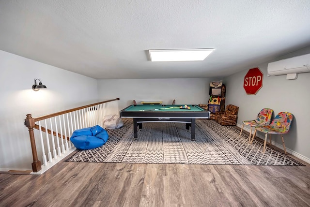 game room with a textured ceiling, wood finished floors, pool table, and a wall unit AC