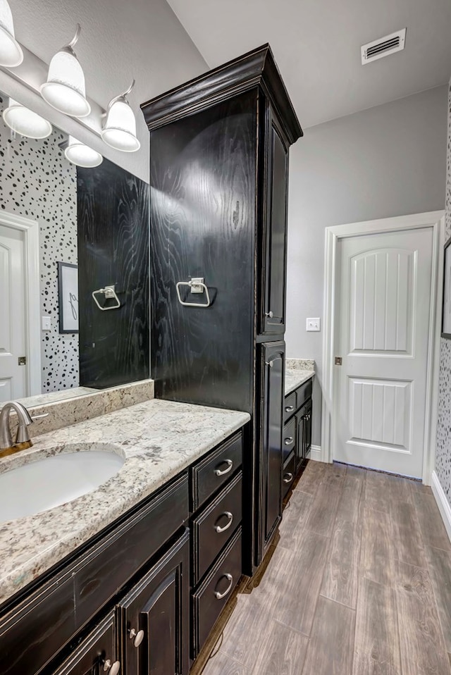 bathroom featuring visible vents, vanity, baseboards, and wood finished floors