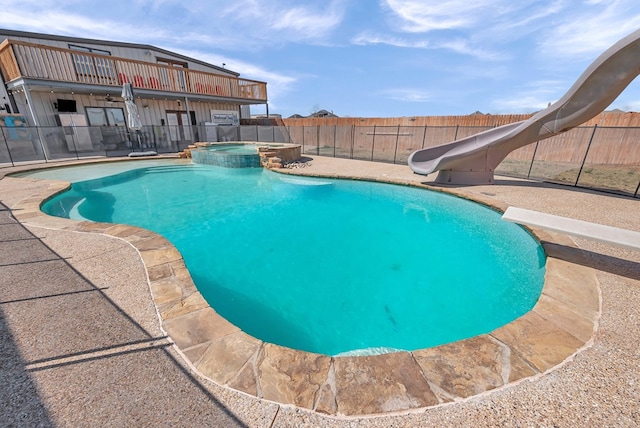 view of pool with a pool with connected hot tub, a fenced backyard, a water slide, a diving board, and a patio area