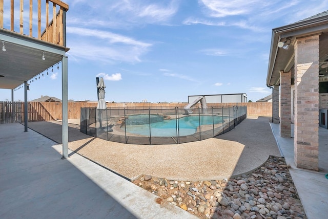 view of pool featuring a fenced backyard, a pool with connected hot tub, a water slide, and a patio