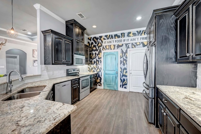 kitchen with visible vents, crown molding, light stone countertops, appliances with stainless steel finishes, and a sink