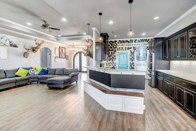 kitchen with decorative backsplash, open floor plan, light wood-style flooring, and arched walkways