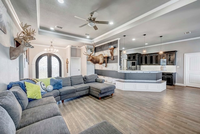 living room with visible vents, french doors, light wood-style floors, and a tray ceiling