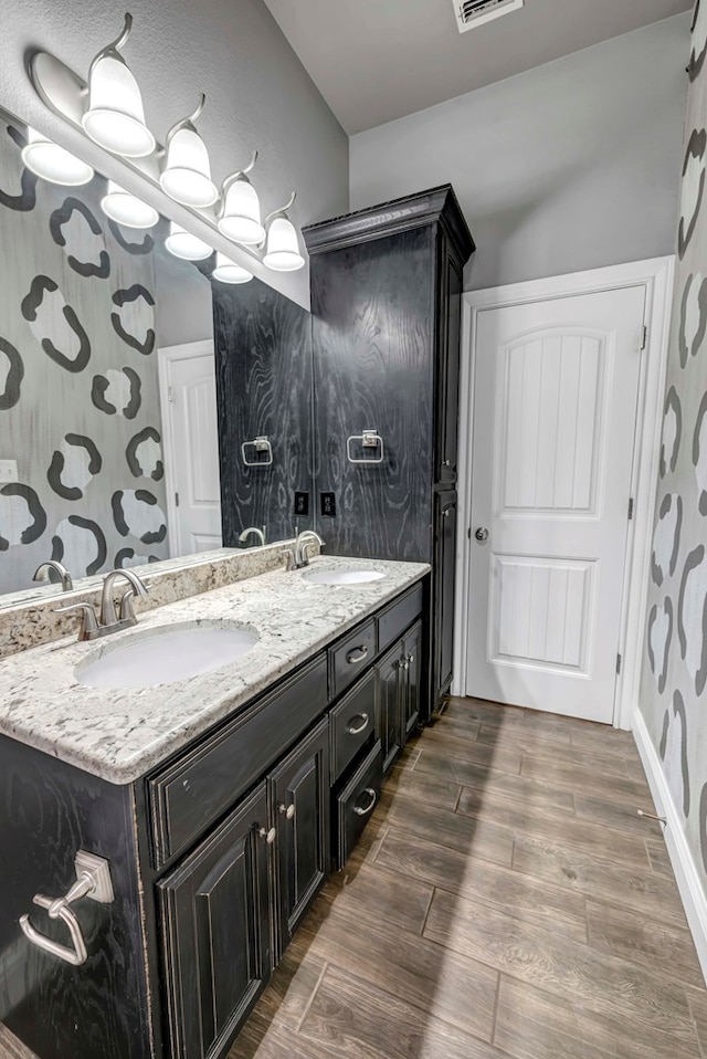 bathroom featuring double vanity, visible vents, wood tiled floor, and a sink