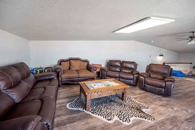 living room featuring lofted ceiling, a textured ceiling, wood finished floors, and a ceiling fan