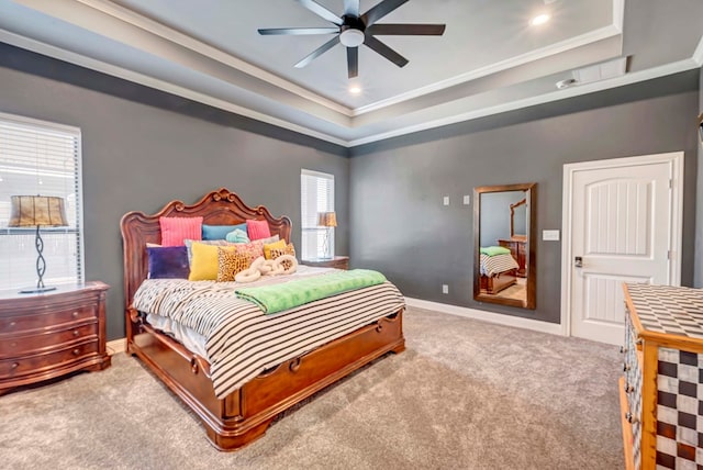 carpeted bedroom featuring baseboards, a raised ceiling, ceiling fan, and crown molding