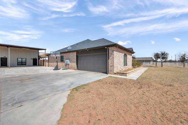 view of side of home with brick siding, fence, concrete driveway, roof with shingles, and an attached garage