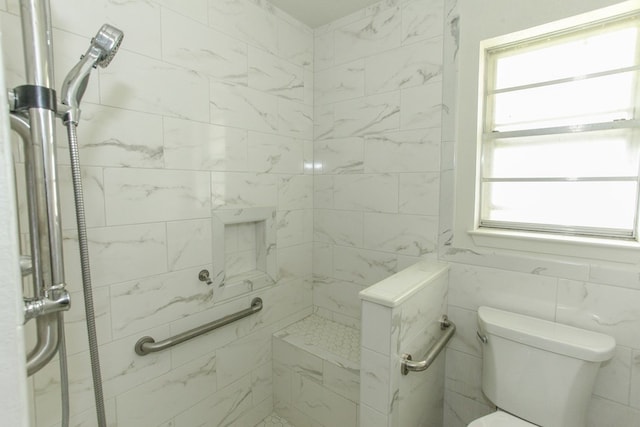 bathroom featuring a tile shower, tile walls, and toilet