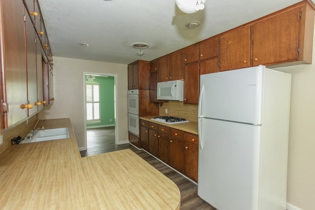 kitchen featuring sink, tasteful backsplash, wood-type flooring, a textured ceiling, and white appliances