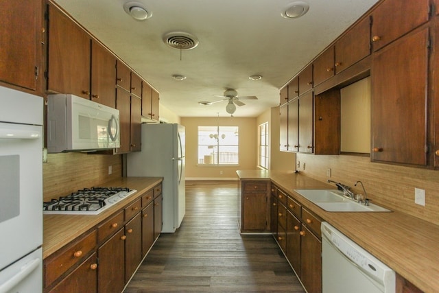 kitchen with white appliances, ceiling fan with notable chandelier, sink, dark hardwood / wood-style floors, and tasteful backsplash