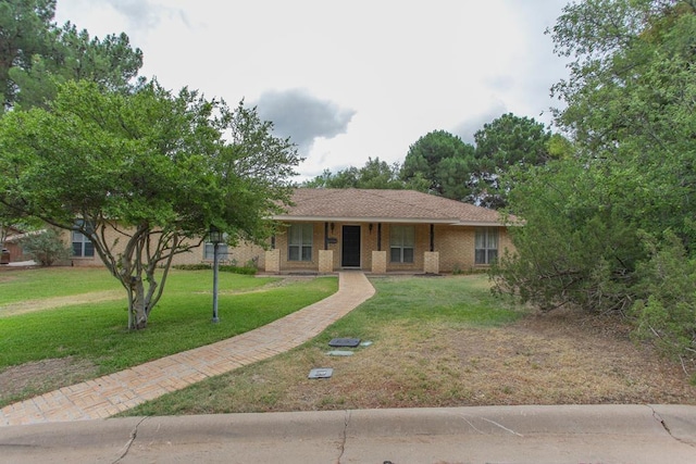 ranch-style house featuring covered porch and a front yard