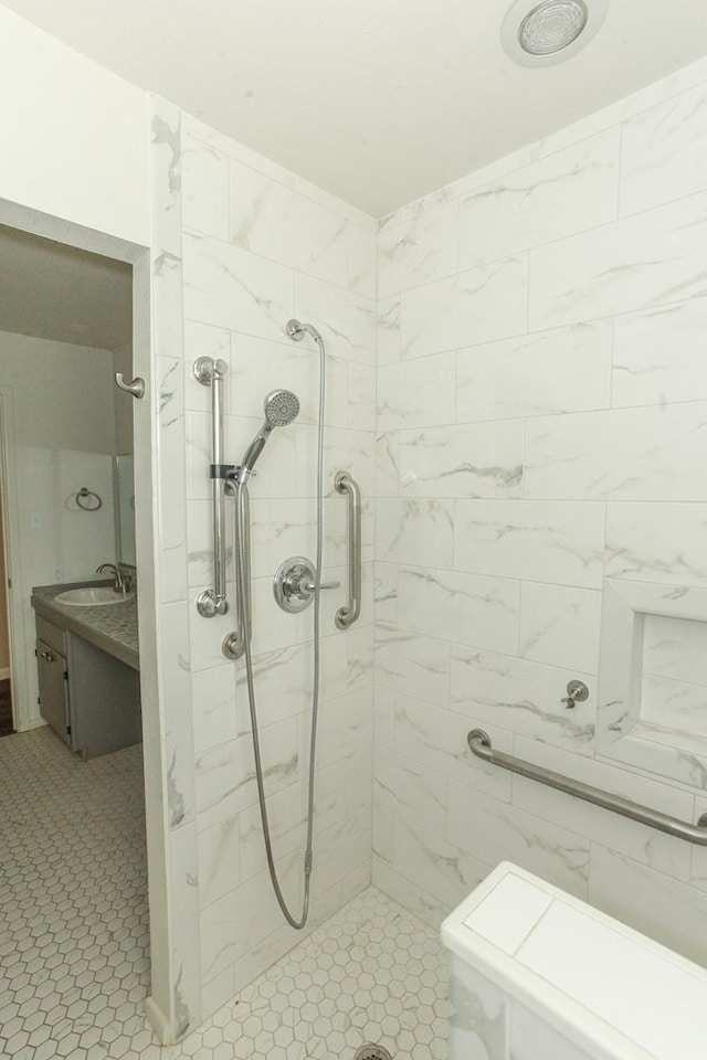 bathroom with a tile shower, vanity, and tile patterned floors