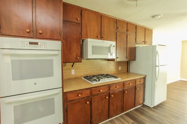 kitchen featuring hardwood / wood-style floors, white appliances, and tasteful backsplash